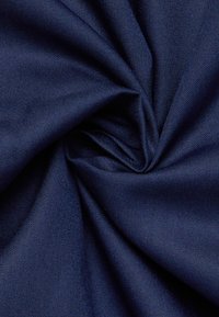 Donkerblauw stof dat in een centrale knoop is gedraaid, met een fijne, gestructureerde weving en gladde, zachte stofplooien.