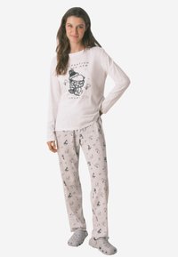 Witte pyjama top met lange mouwen en een zwart cartoonafbeelding. Grijze pyjamabroek met een herhalend patroon van kleine ontwerpen. Grijze slippers.