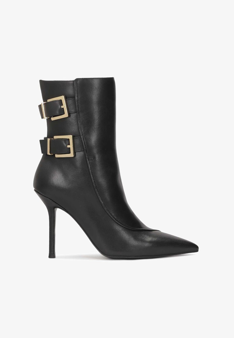 Botină din piele neagră până la gleznă, cu vârf ascuțit și toc stiletto. Prezintă două catarame în ton de aur pe lateral, cu o textură netedă.