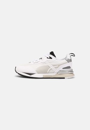 Biało-beżowy sneaker Puma z czarnymi akcentami, panelami z siateczki, wyściełanym kołnierzem i pętelką, pokazany z boku na gładkim tle.