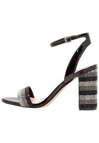 Svart lackläder sandalett med ankelsnodd, försedd med en glittrande, prydd klack i blockformat och ett brett, skimrande band över tån.