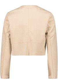 Chaqueta corta beige con mangas largas, textura suave y diseño minimalista. Presenta un detalle limpio y recto en la costura trasera.