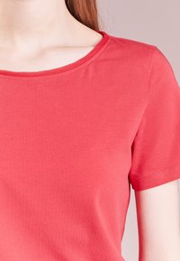 T-shirt rosso a maniche corte con scollatura rotonda, realizzato in tessuto morbido e liscio, presenta un design aderente e dettagli di cucitura minimali.