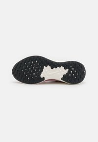 Semelle extérieure noire avec texture en motif, semelle intermédiaire blanche et partie supérieure rose. Logo Nike notable sur la semelle intermédiaire.
