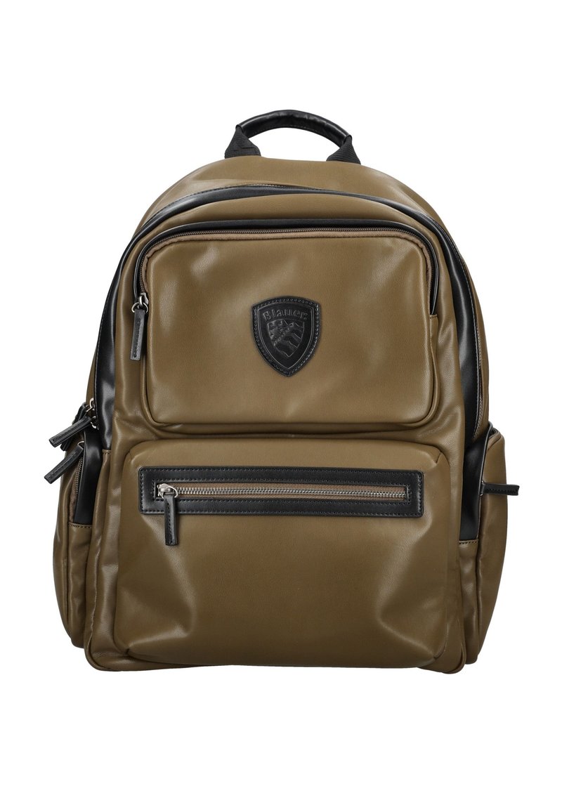 Mochila caqui fabricada con material sintético que presenta una textura suave, acentos negros, múltiples cremalleras y un logo de escudo en la parte frontal.