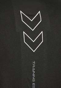 Tissu noir avec deux chevrons blancs délimités vers le bas empilés et le texte « TRAINING ES » en petites lettres grises en dessous.