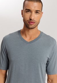 T-shirt grigia a scollo a V con maniche corte, realizzata in tessuto morbido. Caratterizzata da una texture liscia e da una vestibilità casual.