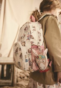 Rucsac alb cu modele animal și motive colorate, având accente roz și un pandantiv în formă de cal atașat la fermoar.