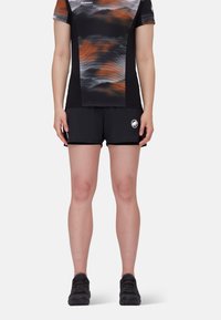 Svart atletiska shorts med en åtsittande design, kombinerat med en kortärmad topp med ett abstrakt mönster i orange och grått.