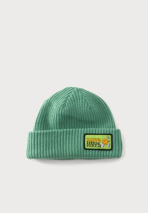 Bonnet tricoté vert avec bord replié comportant un écusson portant la mention "HAPPY little HIKER" avec un visage souriant et un motif de fleur.