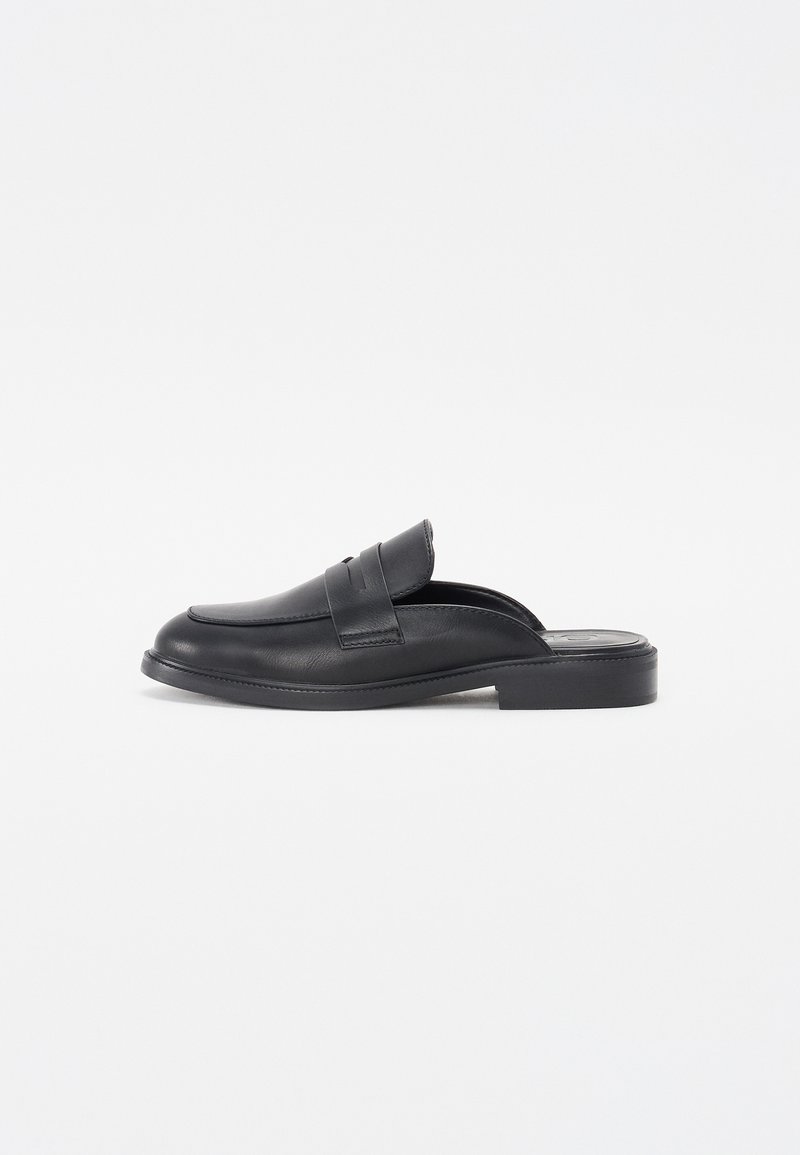 Black leather slip-on shoes with a rounded toe and a low block heel. Features a decorative strap across the upper and smooth texture.