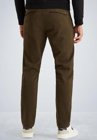 Mørke olivengrønne bukser med en tætsiddende pasform, lavet af glat stof, med to baglommer og båret med hvide sneakers.