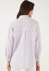 Long-sleeve shirt in light purple with white stripes, featuring a pleated yoke and button cuffs. Smooth fabric with a relaxed fit.