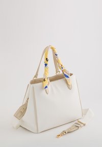 Witte synthetische handtas met gestructureerde vorm, beige accenten en gouden hardware. Bevat dubbele handgrepen gewikkeld in een gele, patroon gescarf.