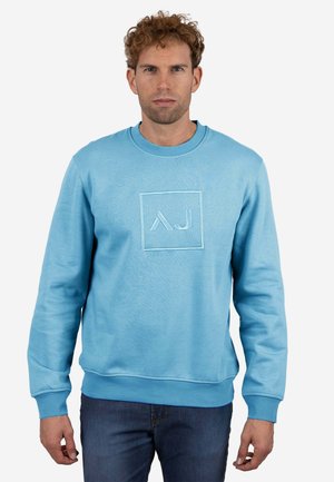 Sudadera azul claro de algodón, con un logo cuadrado que tiene las iniciales bordadas "AJ" en el centro. Textura suave, cuello redondo.