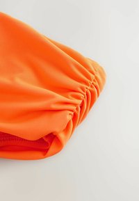 Feloraange stof met een gladde textuur, met geplooide details aan één rand, die een rekbare en strakke pasvorm toont.