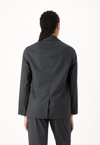 Grå randig kavaj med långa ärmar och en skräddarsydd passform. Har en enda bakventil och en mjuk, texturerad yta.