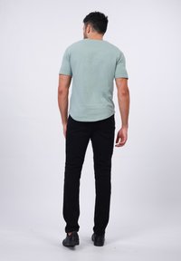 Camiseta de color verde claro, de manga corta, material de algodón; combinada con unos vaqueros negros de corte ajustado, mezcla de algodón; llevada con zapatos negros.