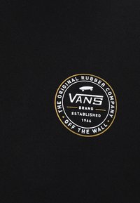 Tessuto di cotone nero con un logo circolare bianco e oro. Il testo include "VANS," "THE ORIGINAL RUBBER COMPANY," e "OFF THE WALL."