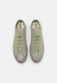 Baskets en tricot vert avec des lacets vert clair, dotées d'un bout en caoutchouc texturé gris moucheté et coloré, et d'une semelle intérieure avec logo.