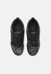 Adidași negri din suede cu un superior texturat din catifea gri, șireturi negre și o talpă din cauciuc, având un design simplu și o construcție plată.