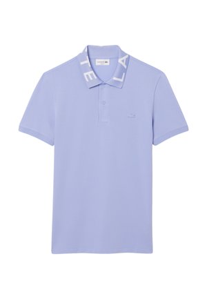 Polo de color púrpura claro, hecho de una tela suave, con un cuello acanalado que lleva la palabra "LACOSTE" impresa, tres botones y un pequeño logotipo en el pecho.
