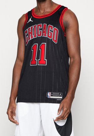 Sort Chicago basketballtrøje med røde kanter og nummer 11, båret af en person i hvide shorts med stort sort Nike-logo.