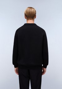 Felpa nera con collo a giro e maniche lunghe raglan. Realizzata in tessuto morbido, presenta polsini e vita a costine. Design semplice e minimalista.