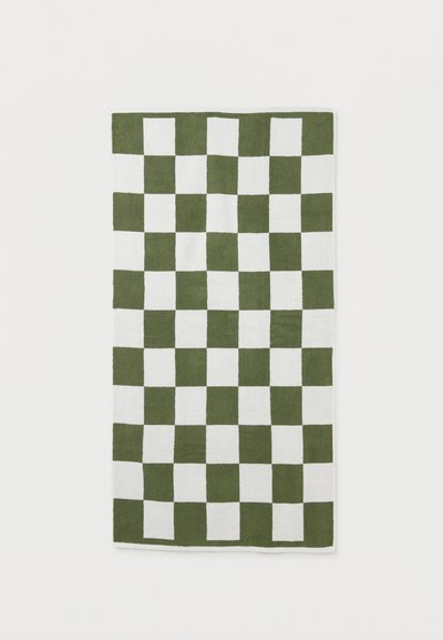 Πράσινο και λευκό τετραγωνισμένο ορθογώνιο χαλί με ομοιόμορφα κατανεμημένο τετραγωνικό μοτίβο, απλωμένο επίπεδα σε λευκή επιφάνεια.