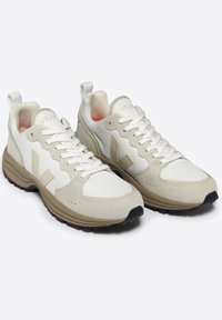 Beige and cream athletic shoes with mesh and suede materials, lace-up design, padded tongue, and textured rubber outsole.