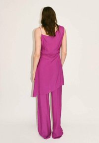 Paarse two-piece outfit met een mouwloos top in een vloeiende stijl en wijde broekspijpen, gemaakt van een lichte, gestructureerde stof.