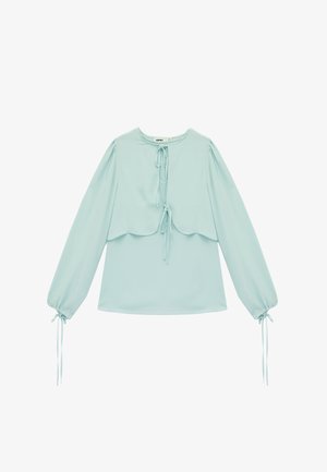 Lichtblauwe blouse met lange mouwen, voorzijde met striksluitingen, gerimpelde manchetten met strikken en een gelaagd, cape-achtig detail op de bovenborst.