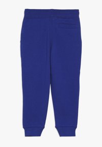 Pantalones de chándal azules hechos de una tela suave, con una cinturilla ajustada, puños elásticos y un pequeño bolsillo trasero. Textura suave sin patrones.