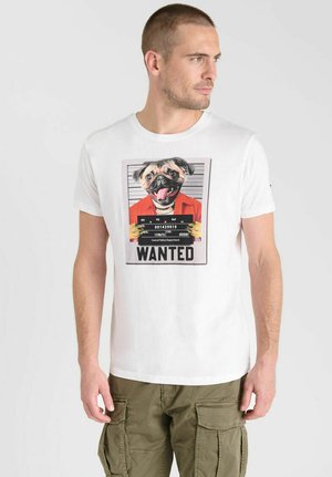 Camiseta blanca de manga corta con un estampado gráfico de un bulldog francés en una camiseta naranja y un fondo de foto policial, etiquetado como "SE BUSCA".