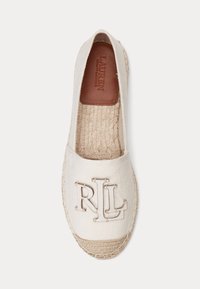 Bela espadrila z tkanim podplatom iz jute, s prišitim logotipom "RL" na zgornjem delu in rjavim usnjenim podložnim vložkom z žigosanim napisom "Lauren Ralph Lauren".