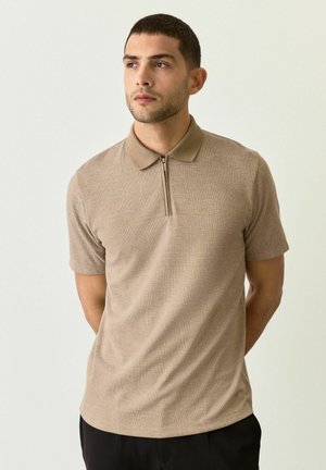 Camisa polo de manga corta beige con un patrón de cuadros texturizado, cuello y cremallera de cuarto. Fabricada con tela liviana.