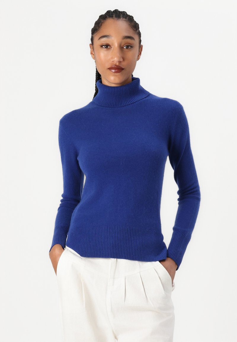 Pull à col roulé bleu en matériau tricot doux. Présente des poignets et un ourlet côtelés, un design ajusté et une texture lisse.