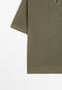 Maglietta a maniche corte verde oliva con scollatura a V, texture a coste e orlo dritto. Presenta cuciture orizzontali su tutta la superficie.