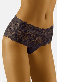 Culotte en dentelle noire avec un motif floral et des bords festonnés, présentant une base en tissu lisse et un design détaillé le long de la taille.