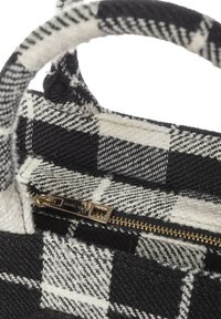 Piccola borsa a mano a quadretti bianchi e neri realizzata in tessuto, con cerniera dorata e manico rotondo. L'interno presenta un motivo a quadretti a contrasto.