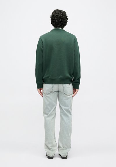 Πράσινο, φούτερ με μακριά μανίκια και ριμπ μανσέτες και τελείωμα. Συνδυάζεται με ανοιχτόχρωμο τζιν με ίσια γραμμή. Πλάτη σε απλό φόντο.