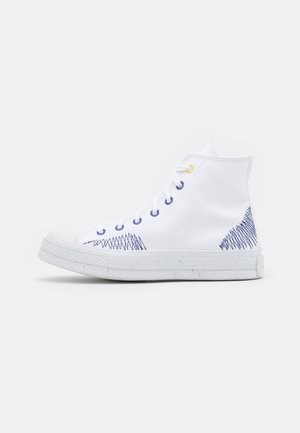 Ténis de cano alto em tela branca com detalhes em costura azul, sola texturizada e detalhes em borracha com polvilho. Design com atacadores, forma clássica.