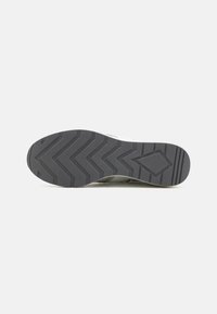 Suola di scarpa con un motivo a zigzag, materiale in gomma grigia, punta arrotondata e colori chiari ai lati. Nessun marchio o logo visibile.