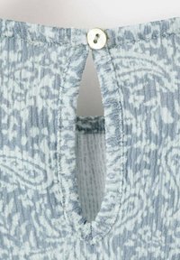 Blått mönstrat tyg med en strukturerad yta, med en rundad halsringning och en liten knappstängning ovanför en nyckelhålsöppning.