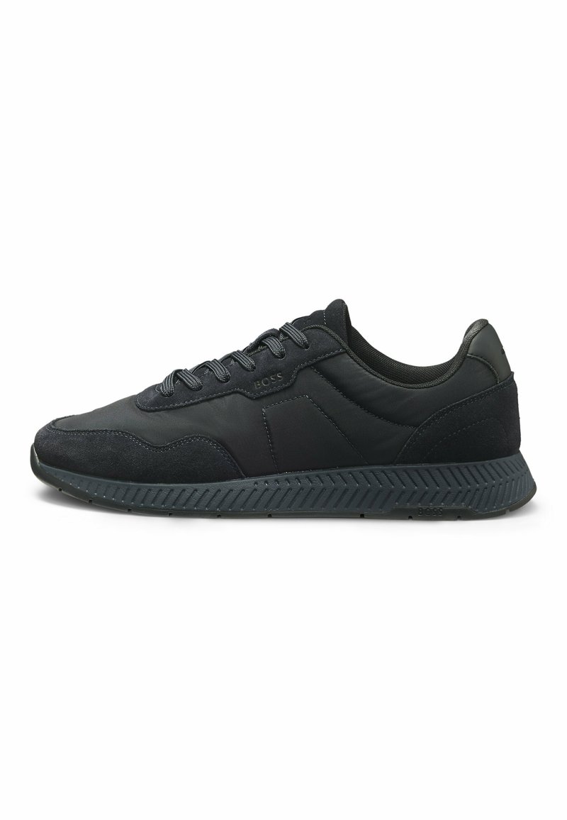 Baskets de sport noires en mélange de cuir lisse et de suède texturé, avec un bout arrondi, des lacets plats et une semelle en caoutchouc à motifs.