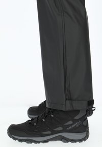 Zwarte wandelschoenen met een gestructureerde stof, verstevigde neus en grijze accenten. Gecombineerd met donkere, stijlvolle waterdichte broek die eindigt bij de enkels.