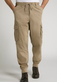 Pantaloni cargo beige con cintura elasticizzata, chiusura con cordino, tasche laterali e polsini a coste. Realizzati in tessuto leggero.