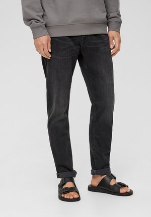 Donkerdenim jeans met een rechte pasvorm, met een subtiele wassing. Gecombineerd met zwarte sandalen, die een gespsdetail en een platte zool benadrukken.