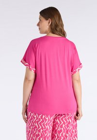 Top de manga corta rosa con puños estampados, textura suave y corte relajado. Combinado con pantalones rosas con un diseño geométrico blanco.