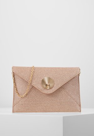 Beige geweven envelop clutch met gouden ronde sluiting en gouden kettingriem, tentoongesteld op een wit oppervlak tegen een grijze achtergrond.